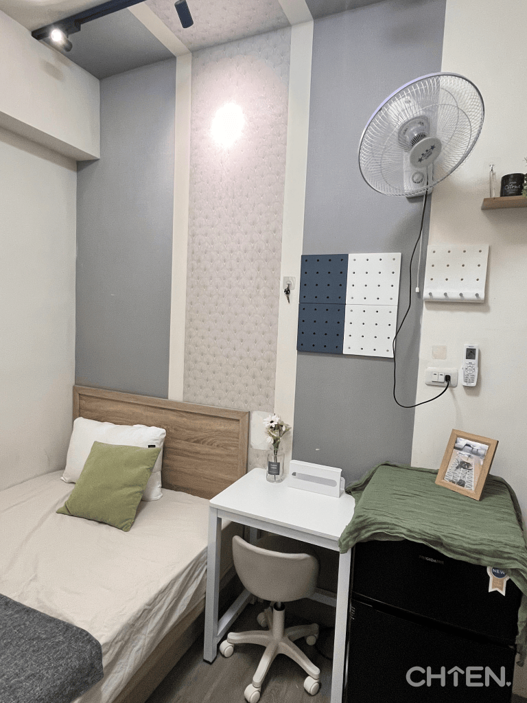 203小套房床鋪布置，淺色寢具搭配灰色床尾毯與綠色抱枕