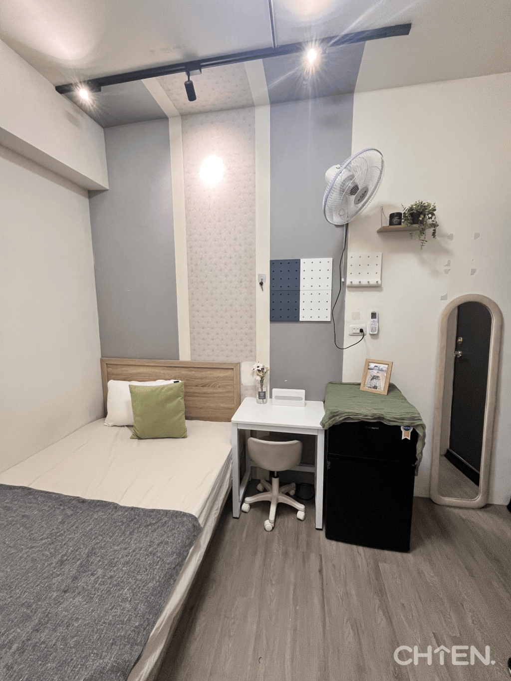 小套房布置全景，呈現床鋪、白色桌椅、冰箱、立鏡與壁面植栽